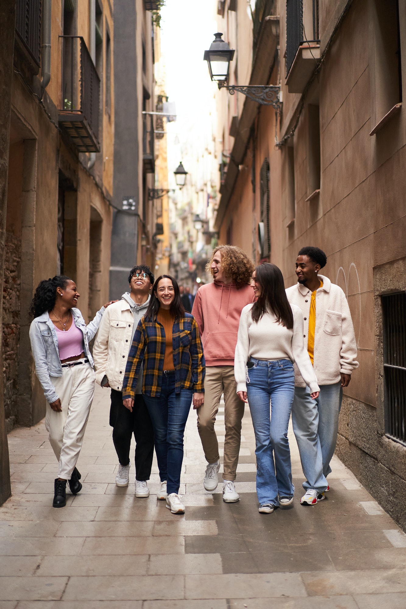 Vertical photo of young happy people walking in the street of the city. Smiling students
